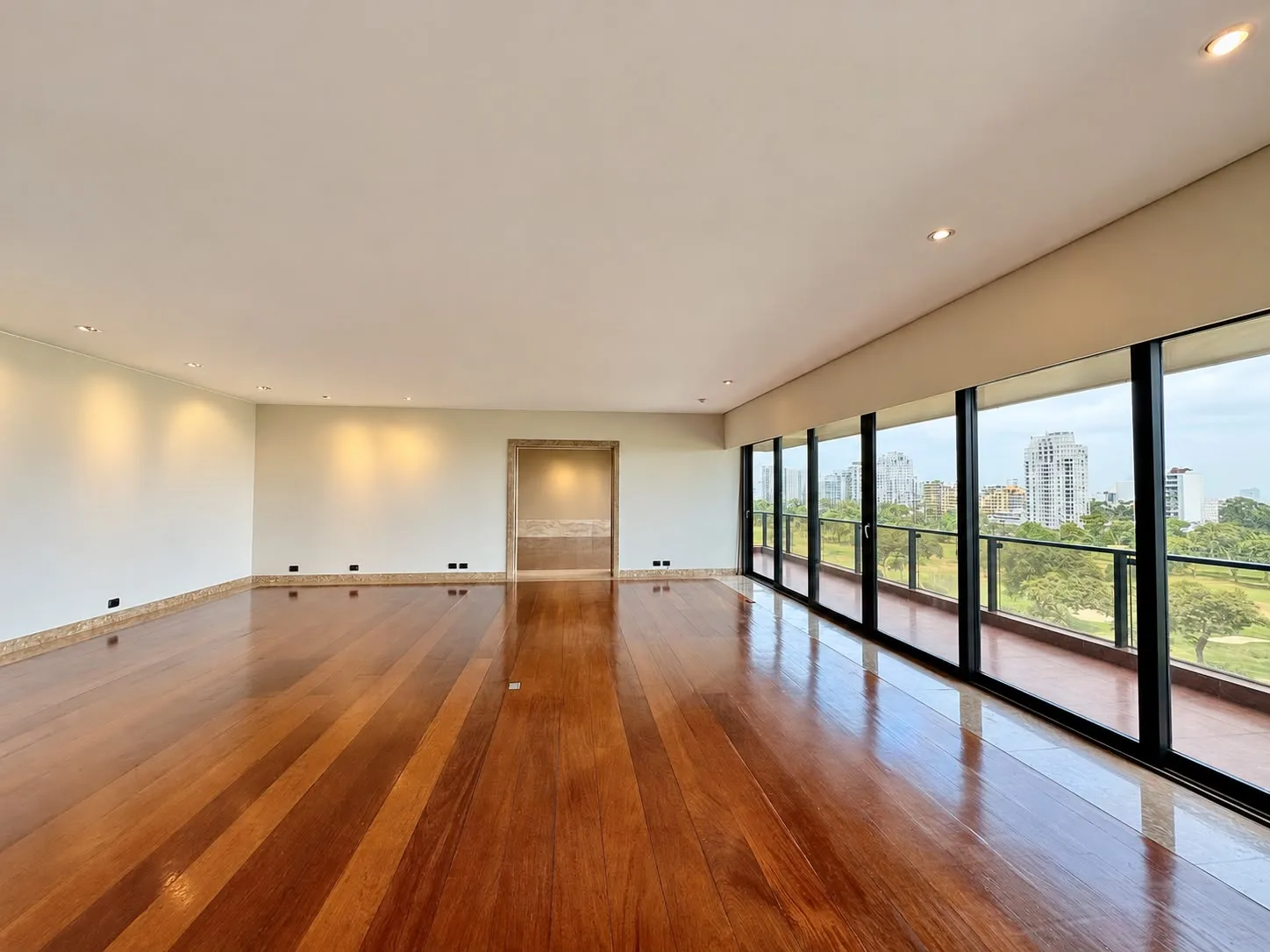 Sala con piso de madera y ventanales hacia el campo de golf