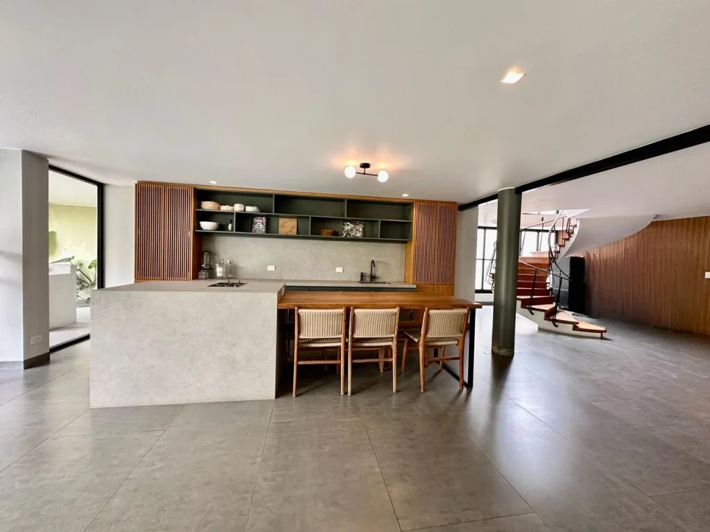 Cocina con isla, barra de madera y escalera