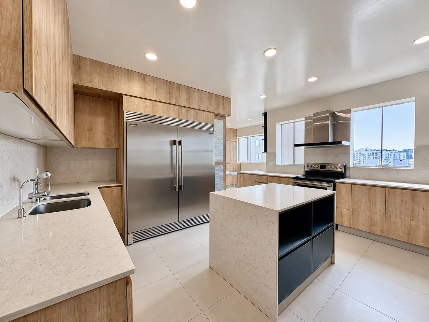 Cocina con refrigeradora de doble puerta, isla y encimeras claras
