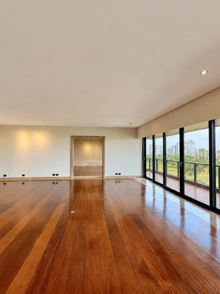 Sala con piso de madera y ventanales hacia el campo de golf